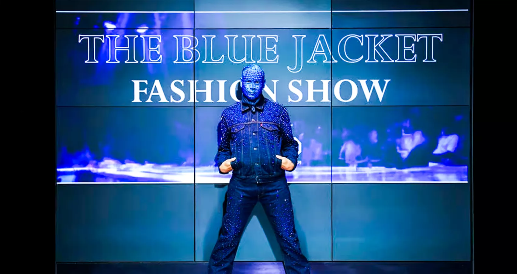 A man wearing sparkly denim with his face fully covered in blue makeup and sequins at the Blue Jacket Fashion Show in 2023