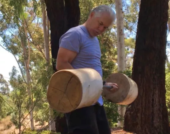 White man lifting handcrafted weights made of out of wood
