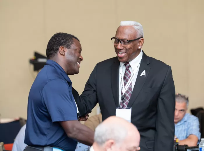 Two African American men shaking hands and smiling
