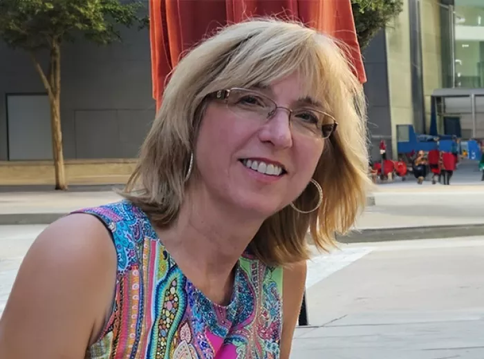 A middle aged blonde woman wearing a colorful shirt